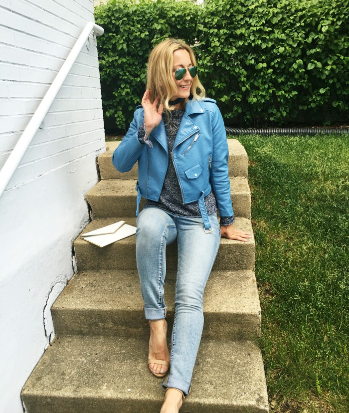 woman sitting on the stairs and wearing Blue sweater and leather jacket