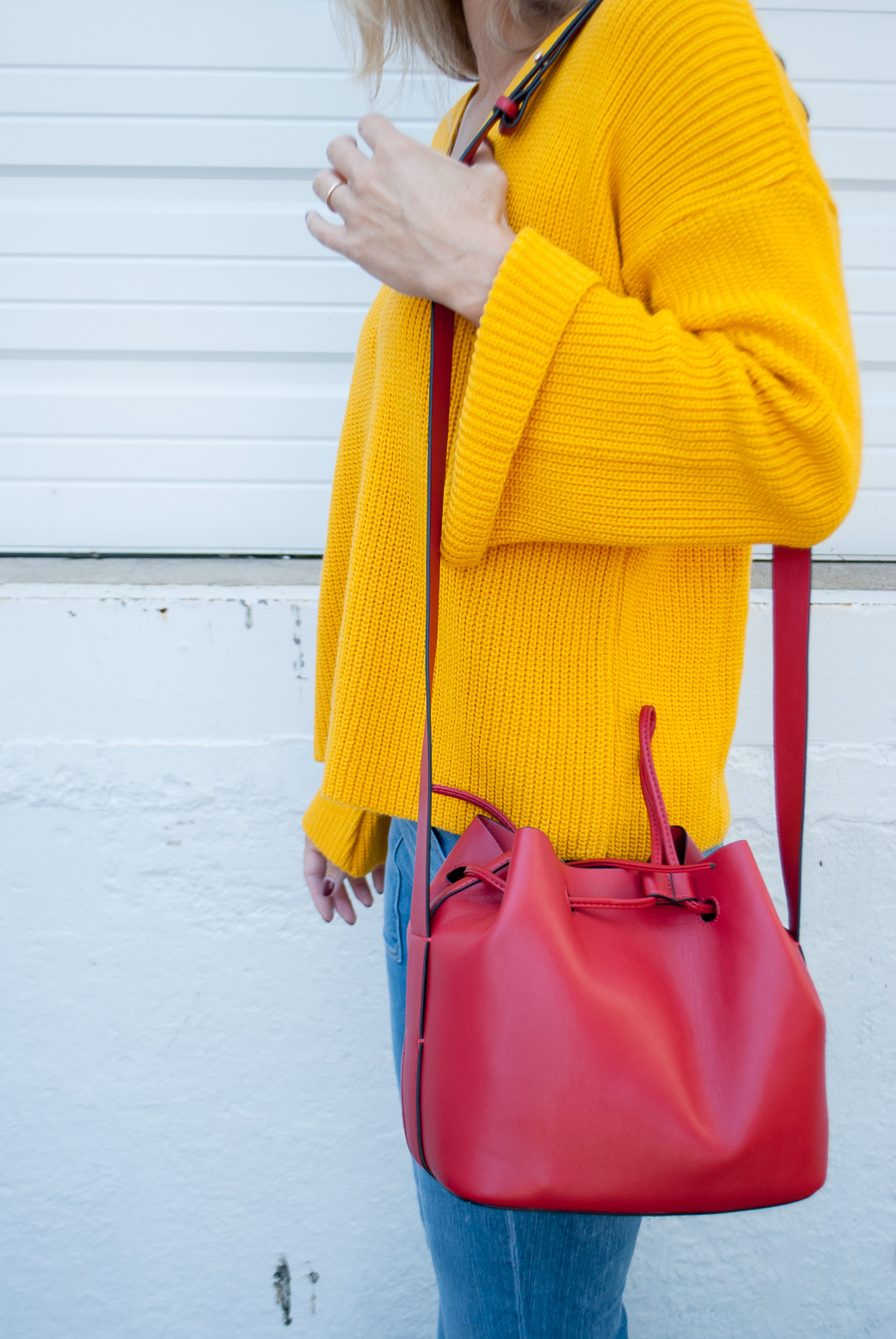 marigold sweater and a red bag