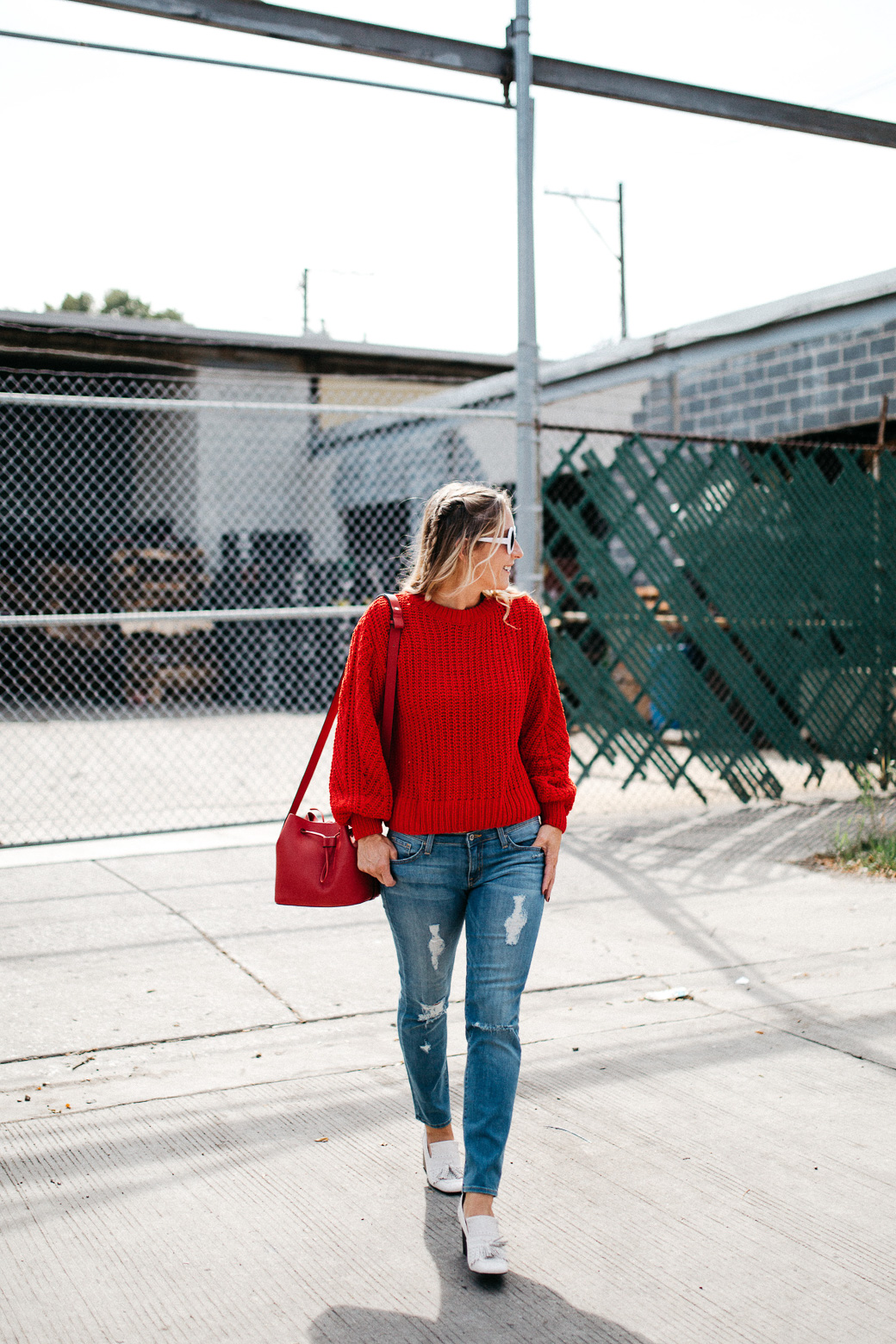 a girl with white shades and a plush way to stay warm for fall with this large item that is red and knitted and long sleeved in the post about 5 Sweaters Needed For Fall