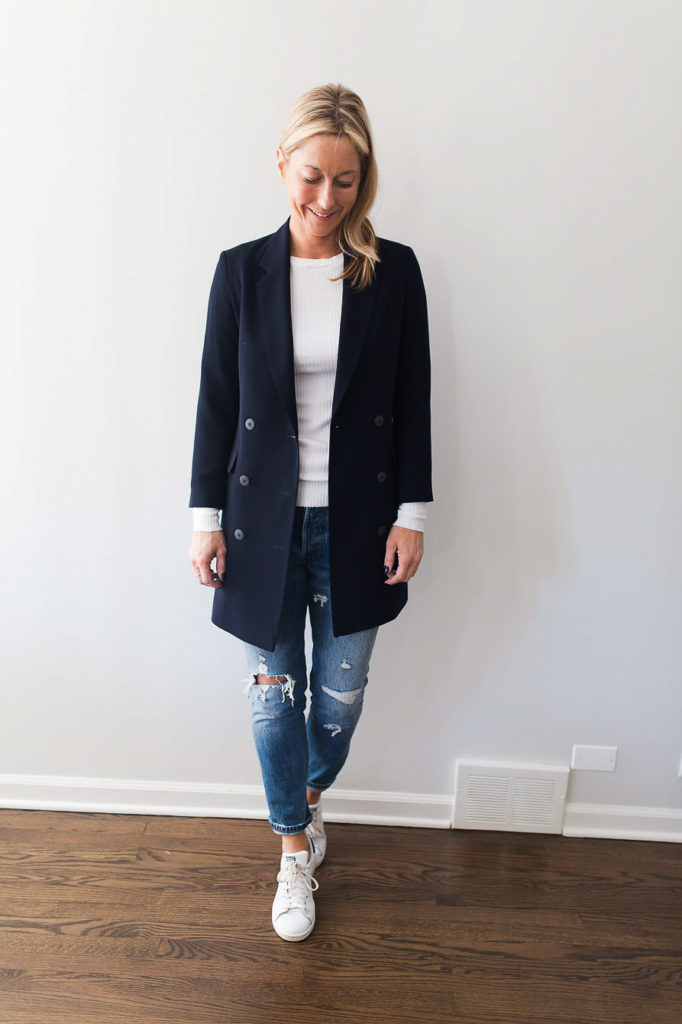 A pair of reto sneakers completes the look of a longer version navy blazer with a white top and distressed denim