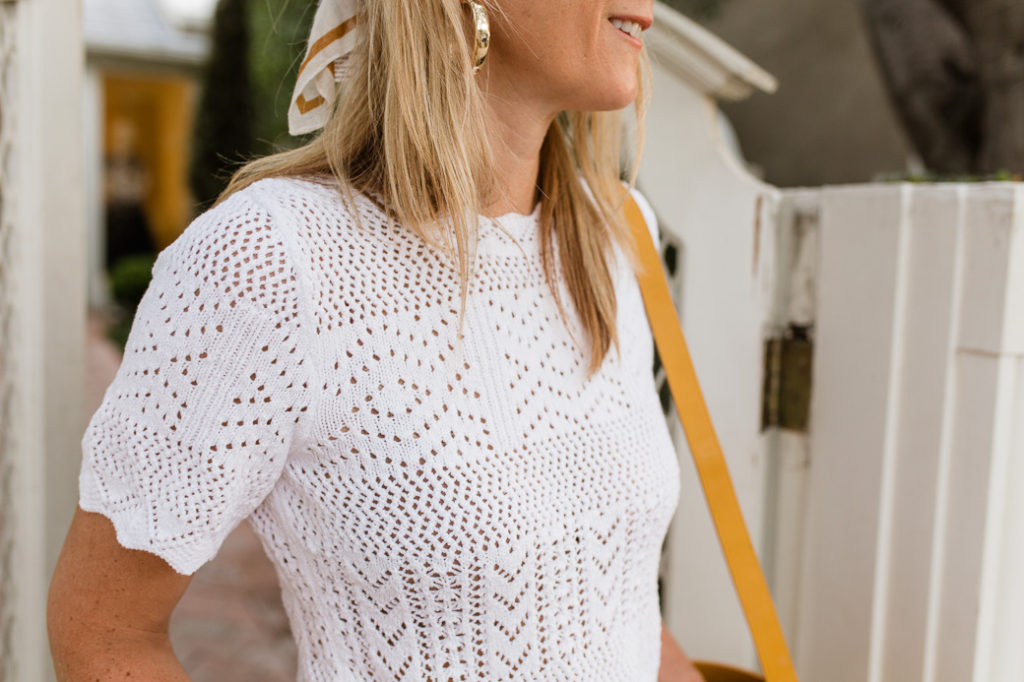 White eyelet top accessorized with gold hoop earrings and a head scarf