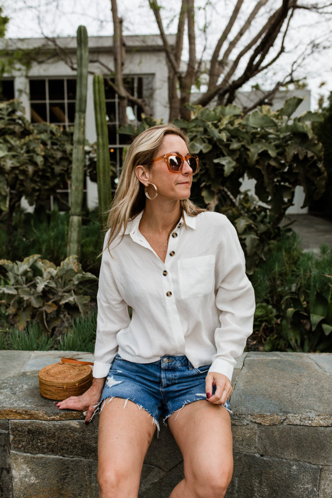 woman sitting and wearing denim shorts and White Essentials for Spring 