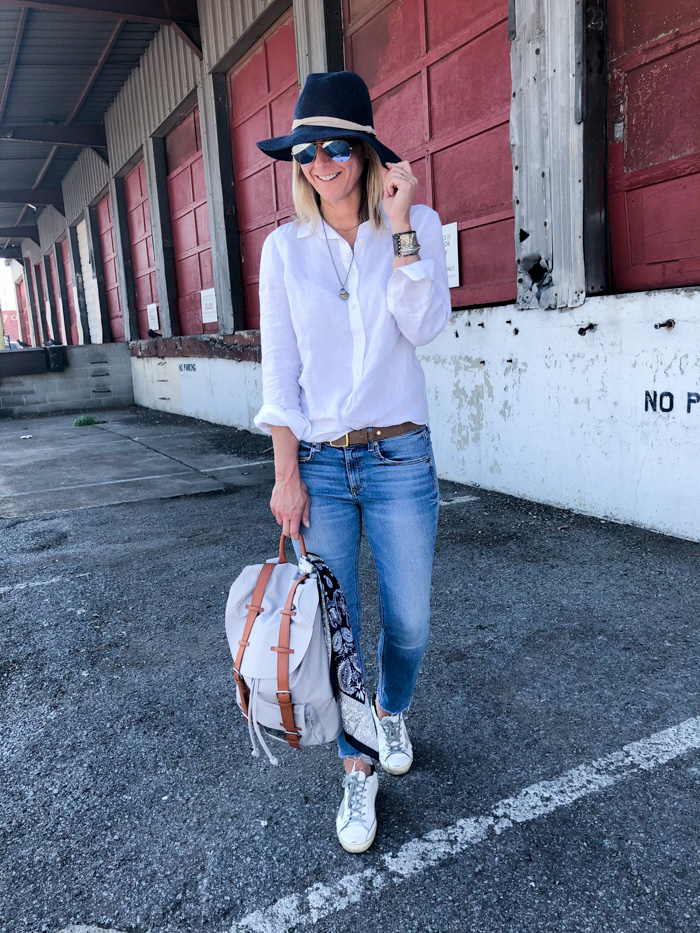 Megan Medica is wearing a white button-down, jeans and sneakers 