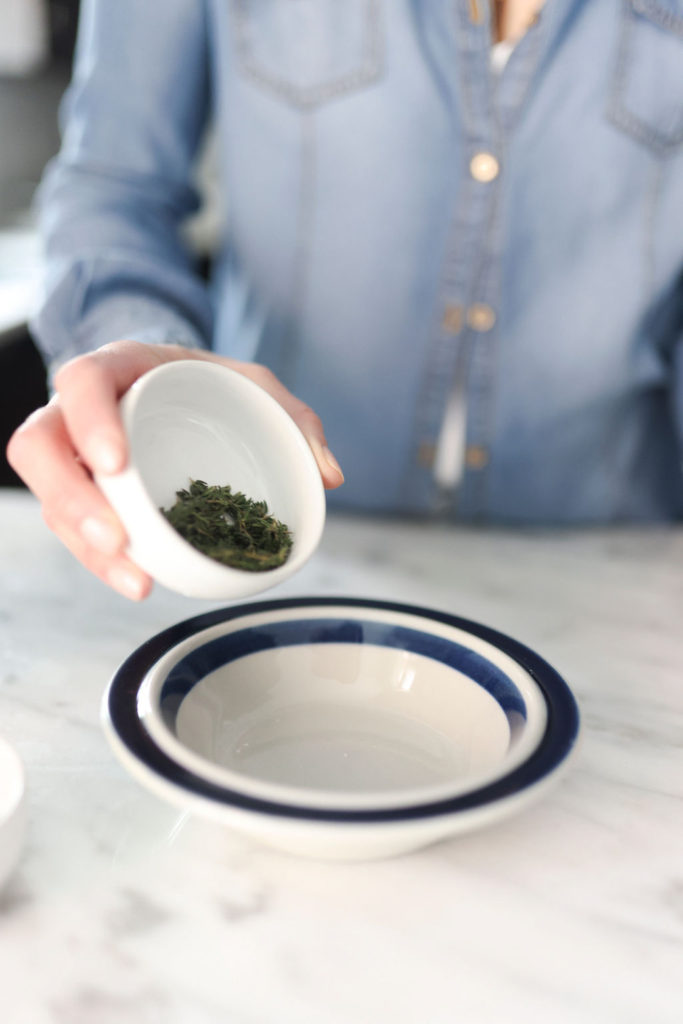 person pouring herbs in a small bowl