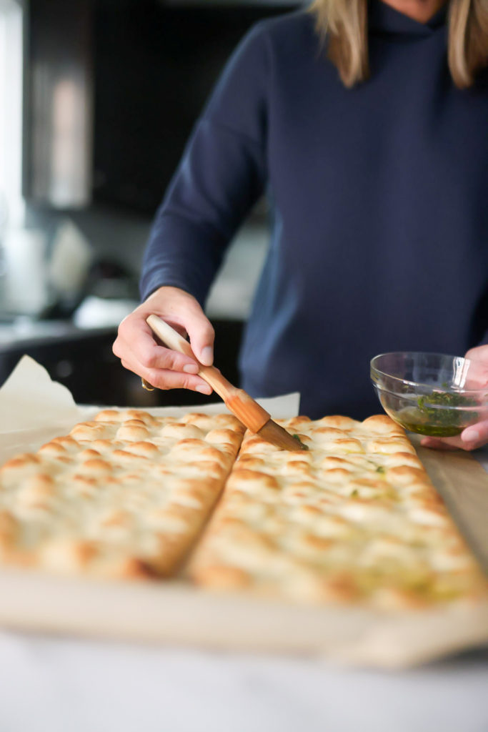 person brushing olive oil on flatbreads