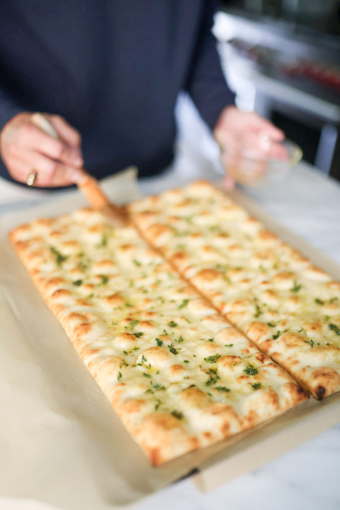 woman adding olive oil on top of a flatbreads