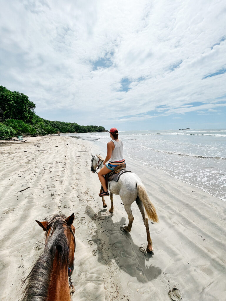 person riding a horse in a shore in a costa rica